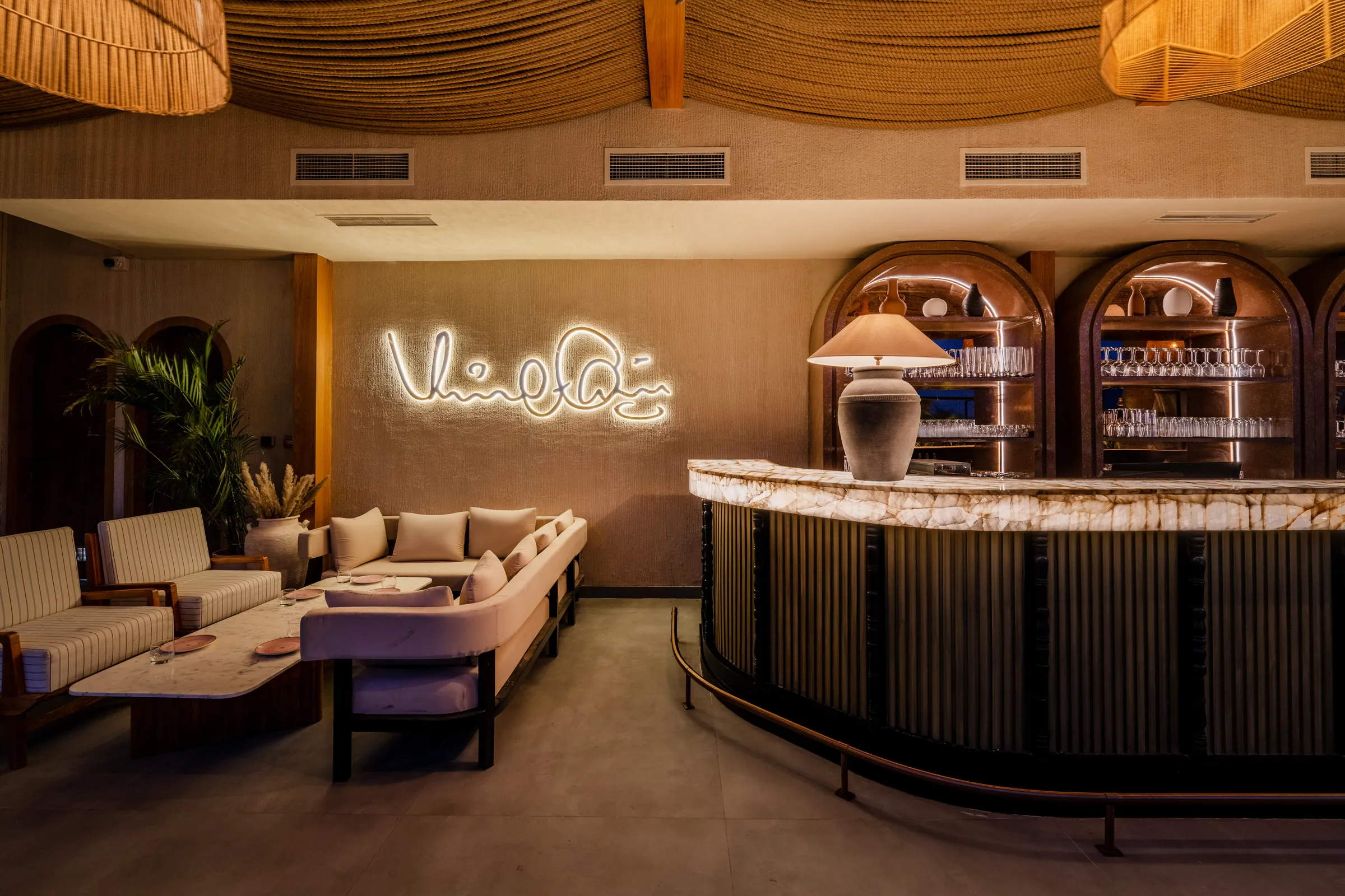 The lounge by the bar — Virat Kohli's signature in neon over a backlit onyx counter