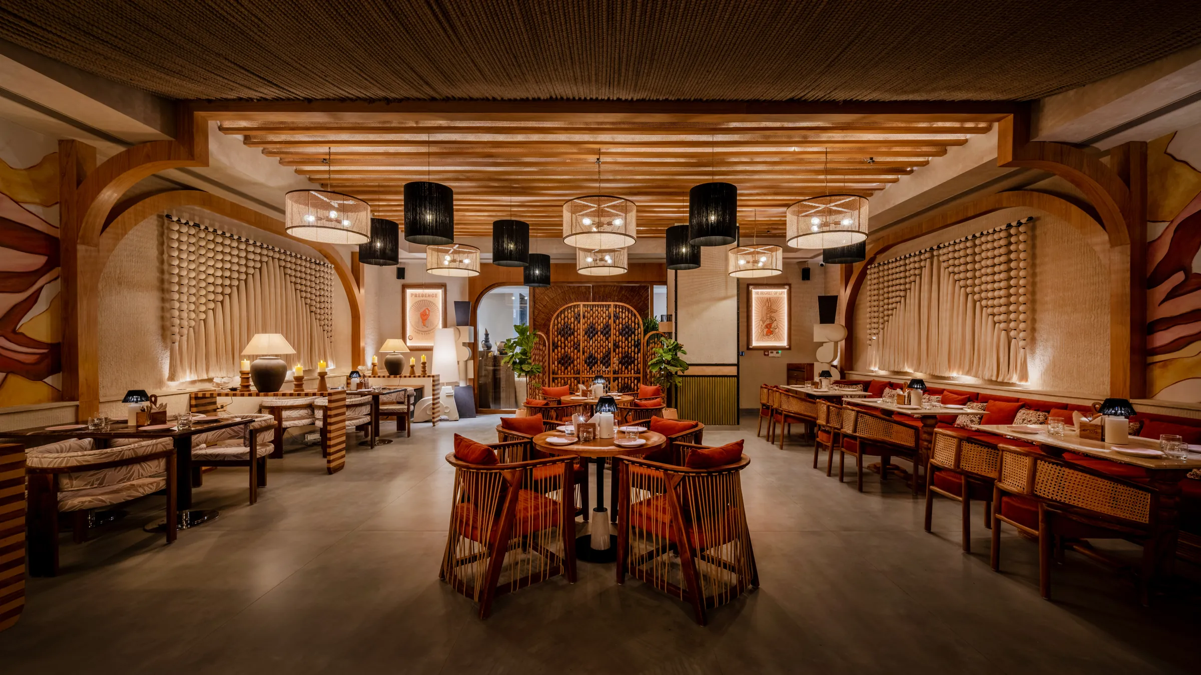 The dining room — oak rafters, woven lanterns and rust-red cane chairs between macramé walls